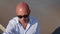 Portrait of a bald man in sunglasses looking up. Close up shot.