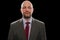 Portrait of a bald mature businessman in grey suit and dark red tie. Black background