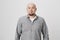 Portrait of bald mature man with beard looking surprised and amazed at camera while standing over white background