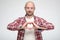 Portrait of a bald, unshaven man who is trying to make a heart shape with fingers and is looking intently at his hands.