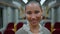 Portrait bald woman smiling to camera at empty train wagon. Happy girl passenger