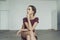 portrait of a ballerina in a half-skirt and knee socks sitting on a chair and looking out the window