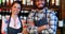 Portrait of barmaid and barman standing with arms crossed at bar counter