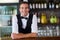 Portrait of bartender leaning on bar counter