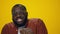 Portrait of bearded african american man dancing on yellow background.