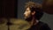 Portrait of bearded drummer performing solo on drum cymbals in recording studio.