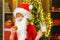 Portrait of bearded funny child in Santa costume. Merry Christmas and happy new year. Santa holding cookie and glass of