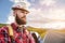 Portrait of a bearded happy serious traveler hipster with a backpack in a plaid shirt and a hat next to an unknown car