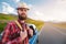 Portrait of a bearded happy serious traveler hipster with a backpack in a plaid shirt and a hat next to an unknown car