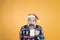 Portrait of bearded hipster in sweater and christmas hat taking a sip of milk on pumpkin color background