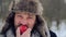 Portrait of a bearded man with an apple in the winter. A young bearded man eats an apple in the winter.