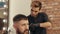 Portrait bearded man getting male haircut in barber shop. Barber cutting hair with electrical shaver and comb in barber