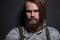 Portrait of a bearded man with an intense look standing in a dark room against a black background