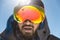 A portrait of a bearded man wearing ski goggles on his way to the top of the mountain. The concept of endurance in the