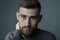 Portrait of a bearded twenty-five year old guy, looking at the camera, psychological portrait on a gray background