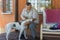 Portrait of bearded Ukrainiansenior man stroking his white mixed breed dog while sitting on summer veranda