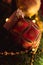 A portrait of a beautifful red christmas ball with sparkling little diamonds on it hanging in a christmas tree. The holiday