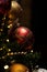 A portrait of a beautifful red glass christmas ball with sparkling little diamonds on it hanging in a christmas tree. The holiday