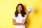 Portrait of beautiful african-american girl, smiling happy and showing money, going shopping, standing over yellow