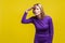 Portrait of beautiful ambitious woman watching far away with hand above eyes. indoor studio shot isolated on yellow background