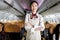 Portrait of beautiful Asian female cabin crew air hostess in uniform standing with arms crossed on aisle inside airplane, woman