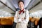 Portrait of beautiful Asian female cabin crew air hostess in uniform standing with arms crossed on aisle inside airplane, woman