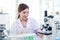 Portrait of beautiful Asian female scientist in lab coats doing science experiments, happy researcher woman using lab equipment