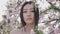 Portrait of a beautiful asian girl outdoors against spring blossom tree.