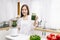 Portrait of beautiful Asian woman making smoothie with fresh vegetables with blender and looking at camera in kitchen at home.