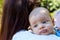 Portrait of beautiful baby with blue eyes and cute face, mother with brown hair caring infant on shoulder, baby burping position