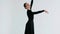 Portrait of a beautiful ballerina in a black dress in a white studio during a classical dance with smooth hand movements