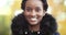 Portrait of beautiful black woman wears warm black jacket stands on street in autumn against background of yellow trees