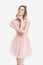 Portrait of beautiful blond dream woman in pink cocktail dress on grey background