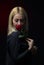 Portrait of a beautiful blonde girl smelling a red rose