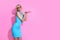 Portrait of beautiful blonde woman in blue dress with sunglasses posing on pink studio background