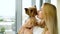 Portrait of beautiful blonde woman holding small fluffy dog kissing her
