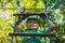 Portrait of a beautiful boy of eleven years in a blue helmet climbing a ladder in a rope park in the summer