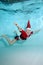 Portrait of a beautiful boy in a Santa Claus hat in a pool underwater. Baby learns to swim underwater. Active happy