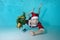 Portrait of a beautiful boy underwater in a Santa Claus costume at the bottom of the pool. He is holding a Christmas