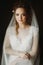 Portrait of beautiful bride, blonde bride in elegant white wedding dress with veil posing in dark room, emotional face closeup.