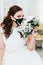Portrait of a beautiful bride with a bouquet in a medical protective mask on her face. Wedding during the period of pandemic Covid