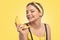 Portrait of a beautiful brunette girl with healthy clean skin and fresh make-up on a yellow background. She holds a banana.