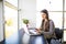 Portrait of beautiful busy woman at home using mobile phone and laptop at the same time in office