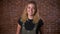 Portrait of beautiful caucasian curly blonde girl standing next to the brick wall relaxed and smiling