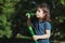 Portrait of a beautiful caucasian girl blows soap bubbles standing in the park