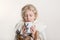 Portrait of beautiful Caucasian girl with closed eyes wrapped in white blanket and drinking from cup. Preschool child covered with