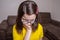 Portrait of a beautiful caucasian girl in a yellow t-shirt pensive, holding her face with one hand