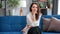 Portrait of beautiful cheerful brunette girl smiling looking at camera sitting on sofa at home.