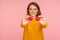 Portrait of beautiful cheerful ginger girl with charming toothy smile and in casual sweater holding little toy hearts, showing