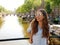 Portrait of beautiful cheerful girl with sunglasses looking to the side on one of typical Amsterdam channels, Netherlands